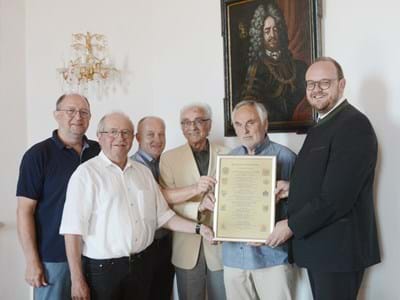Die Kulturfreunde Lobkowitz übergeben die Ahnentafel an Landrat Meier. Im Hintergrund ein Gemälde von Fürst Ferdinand.
